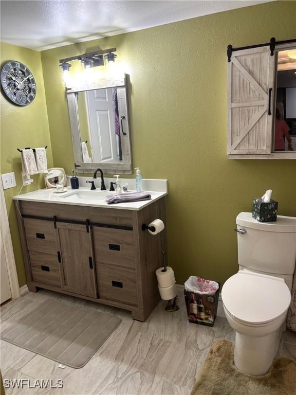 8687 River Homes Ln Unit 4107, Bonita Springs, FL 34135 - half bathroom with a textured wall, vanity, toilet, a textured ceiling, and baseboards