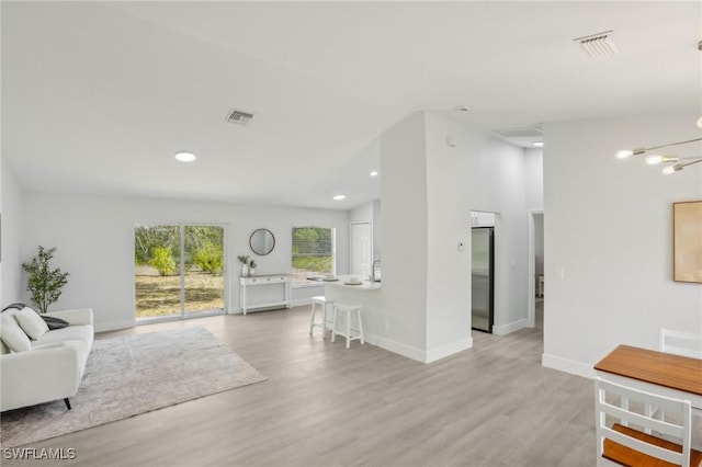 living room featuring visible vents, light wood-style floors, and baseboards