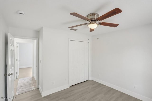 unfurnished bedroom featuring a ceiling fan, visible vents, baseboards, a closet, and light wood finished floors