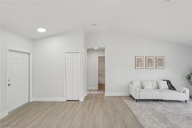 living area with light wood-style floors, baseboards, and vaulted ceiling