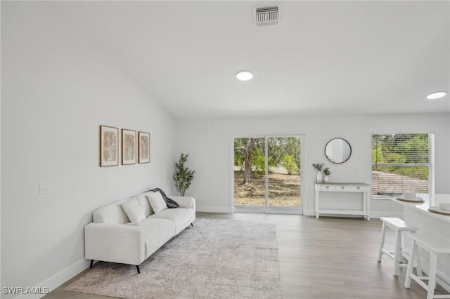 living area featuring recessed lighting, baseboards, wood finished floors, lofted ceiling, and visible vents