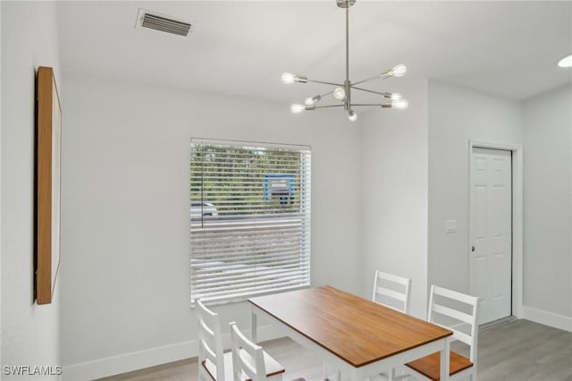 unfurnished dining area featuring a chandelier, baseboards, visible vents, and light wood-style flooring