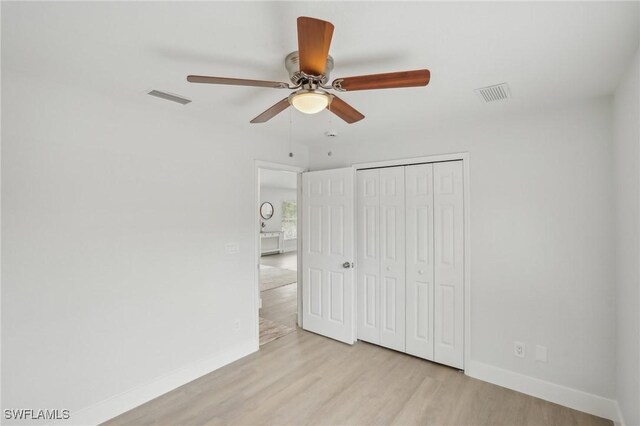unfurnished bedroom featuring a ceiling fan, baseboards, wood finished floors, visible vents, and a closet
