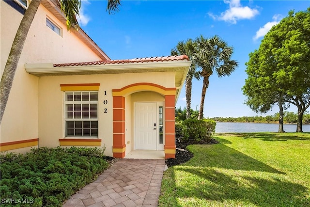 25073 Peacock Ln Unit 102, Naples, FL 34114 - property entrance featuring stucco siding, a yard, a water view, and a tile roof