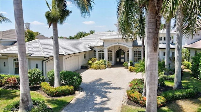 10371 Via Anacapri Ct, Miromar Lakes, FL 33913 - mediterranean / spanish-style home featuring driveway, french doors, a tiled roof, an attached garage, and stucco siding