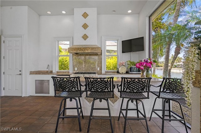 10371 Via Anacapri Ct, Miromar Lakes, FL 33913 - kitchen with stainless steel microwave, a sink, decorative backsplash, and a healthy amount of sunlight