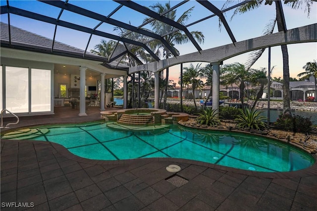 10371 Via Anacapri Ct, Miromar Lakes, FL 33913 - pool at dusk with a patio area, a pool with connected hot tub, and glass enclosure