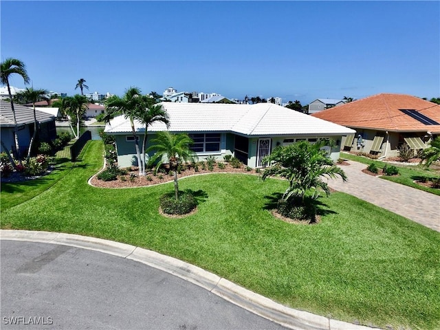 ranch-style house with a tiled roof, stucco siding, driveway, and a front lawn