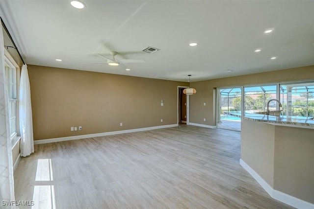 spare room featuring baseboards, ceiling fan, light wood-type flooring, and visible vents
