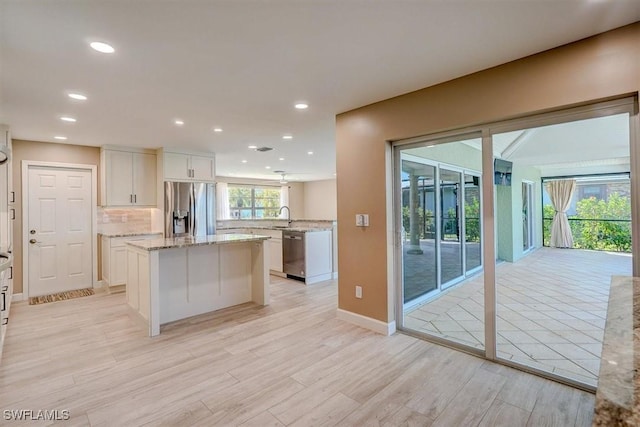 kitchen with recessed lighting, appliances with stainless steel finishes, a kitchen island, and light wood-type flooring