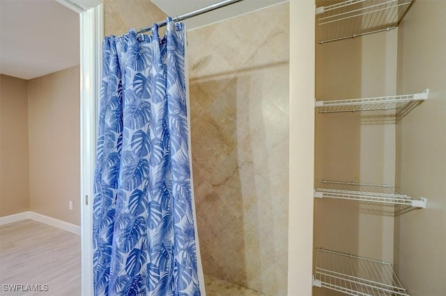full bath with baseboards, a shower with shower curtain, and wood finished floors