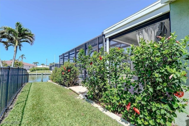 view of yard featuring a water view, glass enclosure, and fence