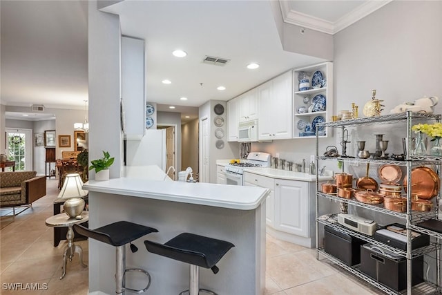 kitchen featuring crown molding, visible vents, a breakfast bar, white appliances, and light tile patterned floors