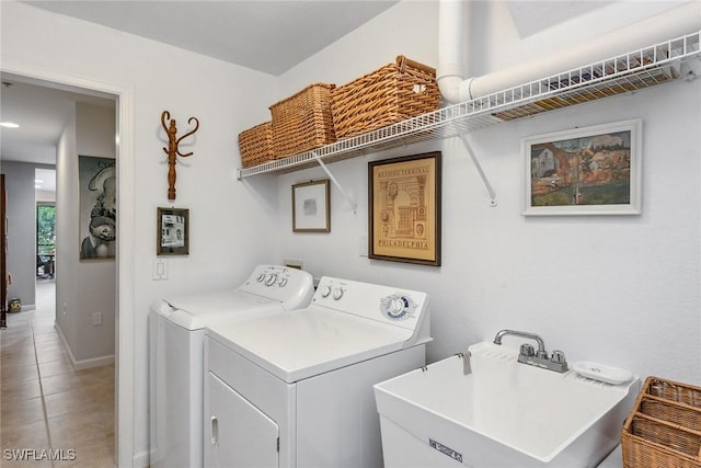 laundry room with laundry area, washing machine and clothes dryer, tile patterned flooring, a sink, and baseboards