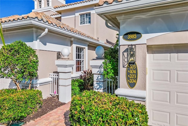 exterior space featuring a garage, a tile roof, and stucco siding