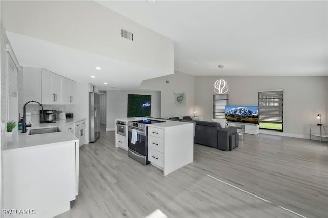 2723 SW 5th Ave, Cape Coral, FL 33914 - kitchen featuring a sink, appliances with stainless steel finishes, light wood finished floors, white cabinets, and open floor plan