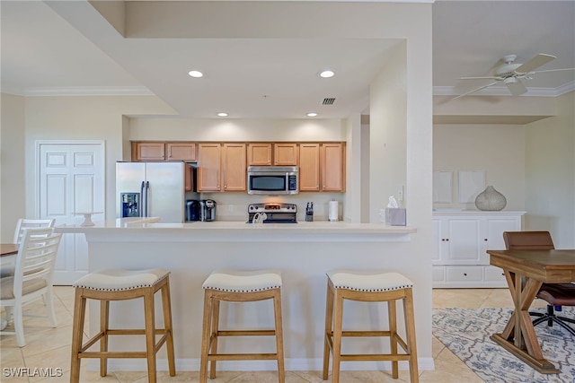kitchen with crown molding, a kitchen breakfast bar, and stainless steel appliances