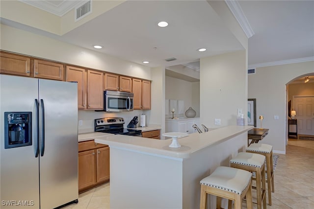 kitchen with arched walkways, stainless steel appliances, light tile patterned floors, a kitchen bar, and visible vents