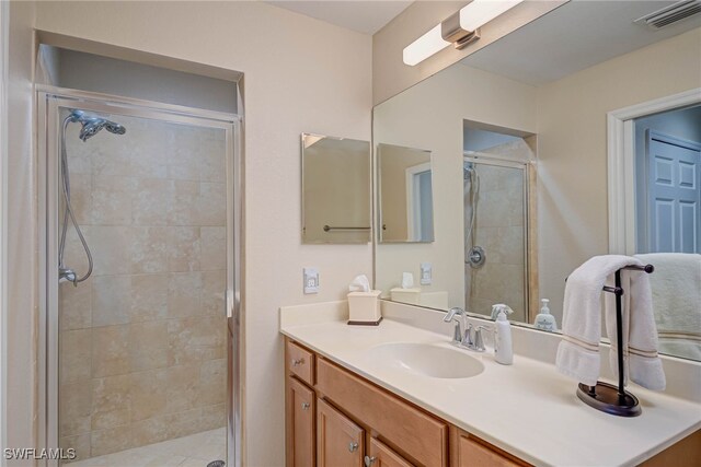 full bath featuring vanity, a shower stall, and visible vents