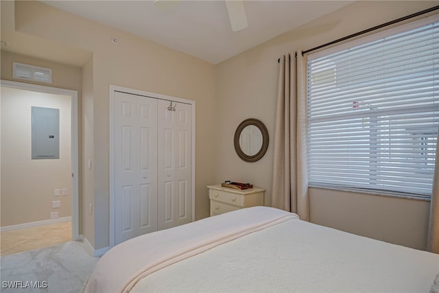bedroom with electric panel, a ceiling fan, baseboards, light tile patterned floors, and a closet