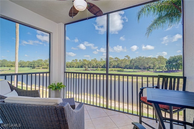 sunroom / solarium with a ceiling fan and a water view