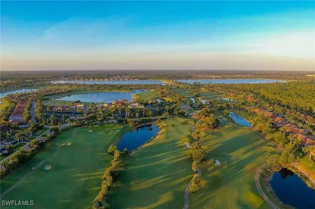 aerial view at dusk featuring a residential view, a water view, and golf course view