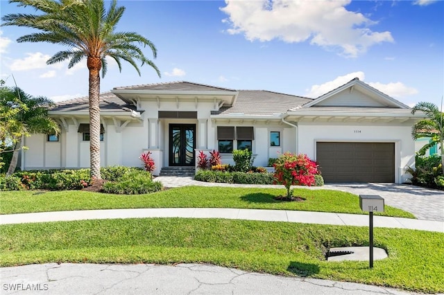 view of front of property with an attached garage, french doors, a front yard, and stucco siding
