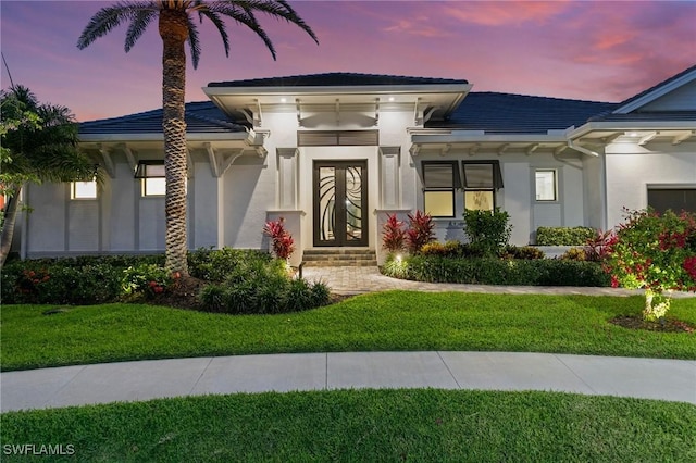 property entrance featuring stucco siding and a yard