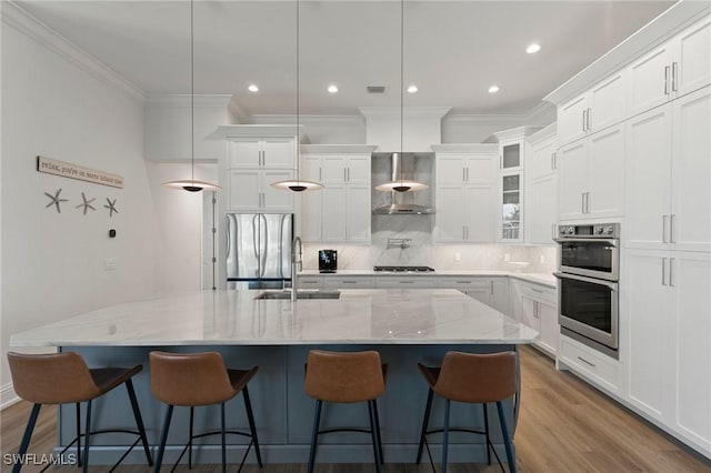 kitchen with decorative backsplash, crown molding, wood finished floors, stainless steel appliances, and wall chimney exhaust hood