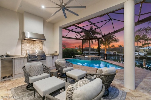 pool at dusk featuring a ceiling fan, glass enclosure, area for grilling, and a patio