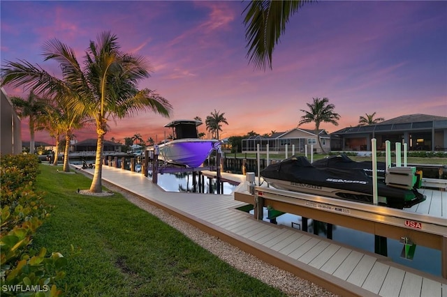 view of dock with a lawn and boat lift
