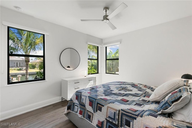 bedroom with a ceiling fan, baseboards, multiple windows, and wood finished floors
