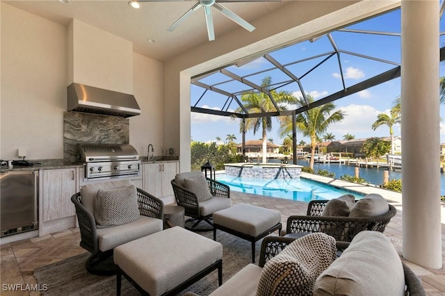 view of patio / terrace with a pool with connected hot tub, an outdoor kitchen, ceiling fan, a water view, and a grill