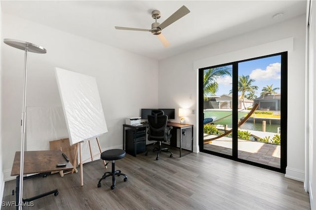 office space featuring a ceiling fan, baseboards, and wood finished floors