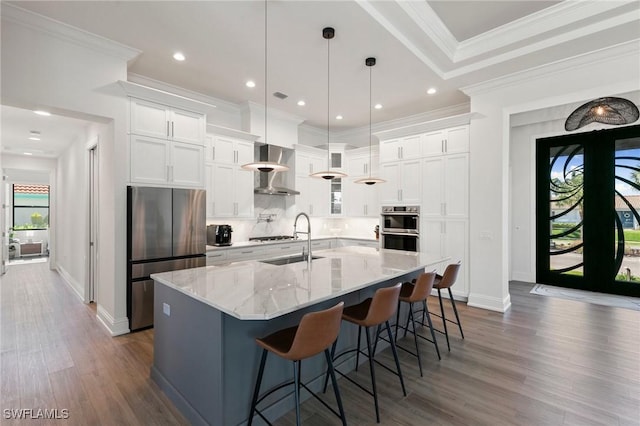 kitchen featuring wall chimney exhaust hood, white cabinetry, a sink, dark wood finished floors, and stainless steel appliances