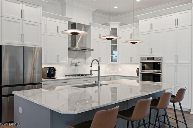 kitchen with white cabinets, appliances with stainless steel finishes, glass insert cabinets, and wall chimney exhaust hood
