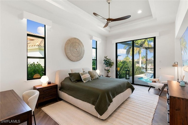 bedroom with access to outside, ceiling fan, light wood finished floors, and a raised ceiling