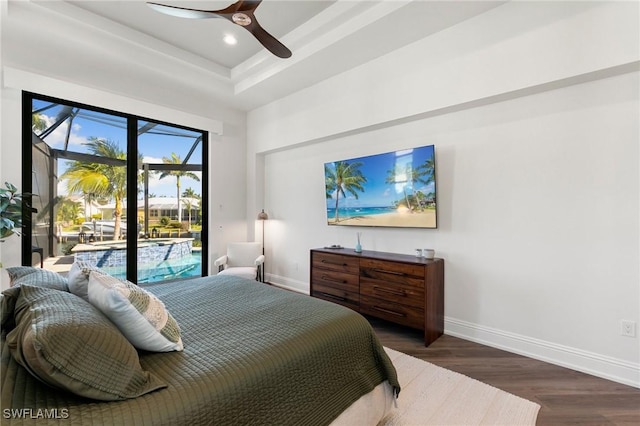 bedroom with baseboards, wood finished floors, a tray ceiling, and access to exterior