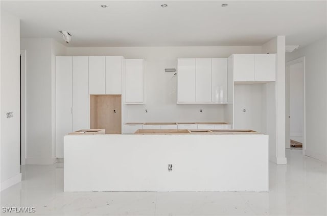 kitchen featuring a kitchen island, white cabinetry, baseboards, and modern cabinets