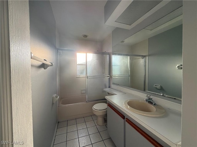 bathroom featuring toilet, combined bath / shower with glass door, tile patterned flooring, and vanity