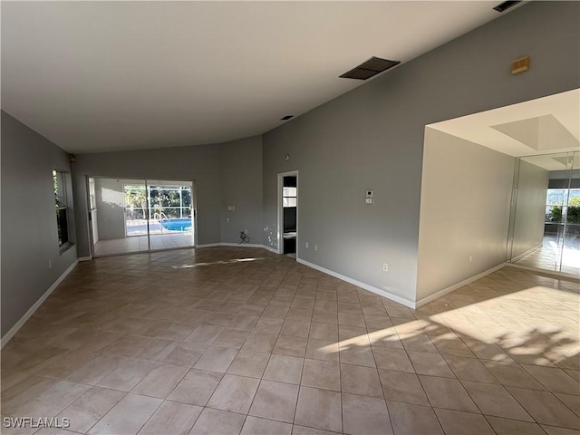 unfurnished room with baseboards, high vaulted ceiling, and a wealth of natural light