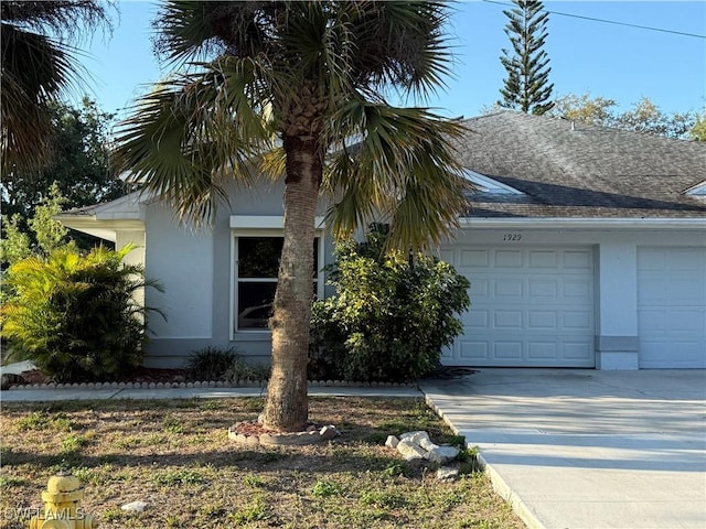 view of front of property with an attached garage, driveway, a shingled roof, and stucco siding