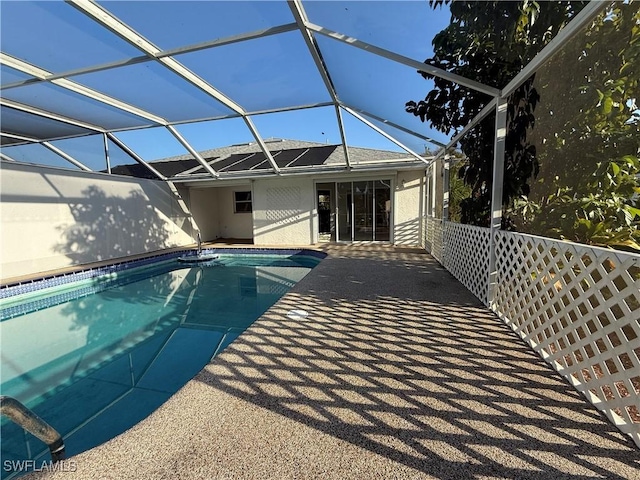 outdoor pool featuring glass enclosure and a patio area
