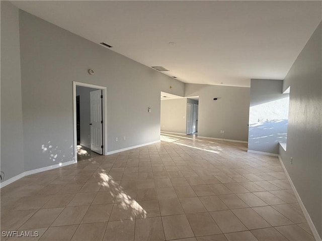 unfurnished room with light tile patterned flooring, baseboards, and lofted ceiling