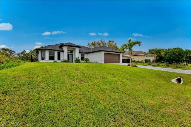 prairie-style home with an attached garage, concrete driveway, stucco siding, and a front yard