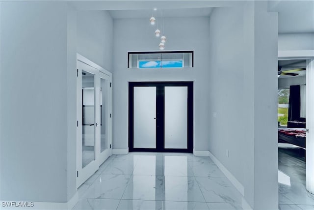 entrance foyer featuring baseboards, a towering ceiling, and marble finish floor