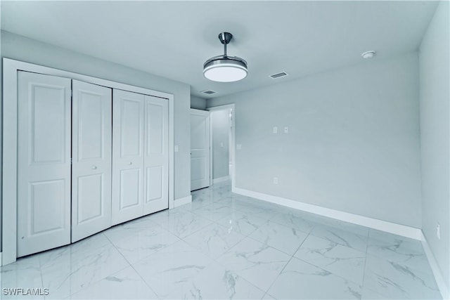 unfurnished bedroom with baseboards, visible vents, marble finish floor, and a closet