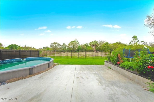 view of swimming pool with a trampoline, a fenced in pool, a fenced backyard, a lawn, and a patio