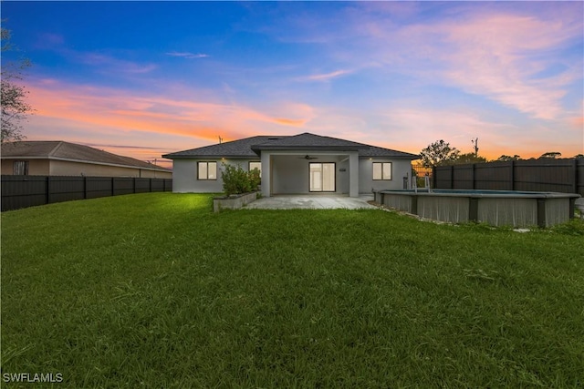 rear view of house featuring a lawn, a ceiling fan, a fenced backyard, and stucco siding