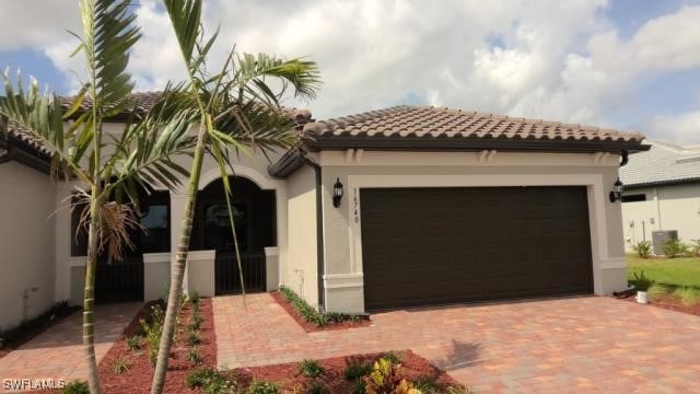 mediterranean / spanish house featuring an attached garage, driveway, a tile roof, and stucco siding